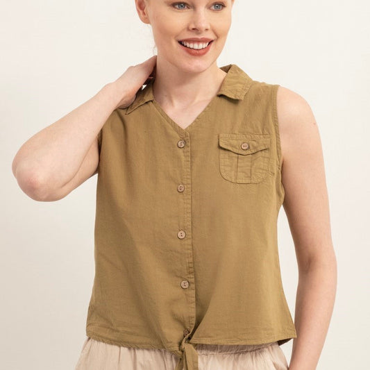 A woman modeling a sleeveless button-front top in a muted olive-brown/khaki color, paired with light beige bottoms, against a plain light background.