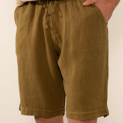 Person wearing olive green shorts with a plain background