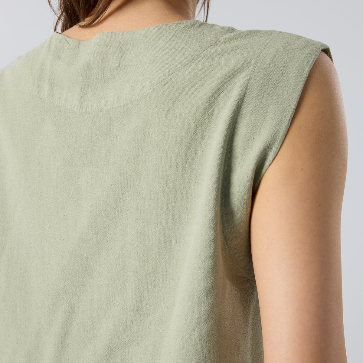 Light green sleeveless top worn by a person on a plain background