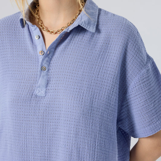 Blue textured shirt worn by a person on a light gray background
