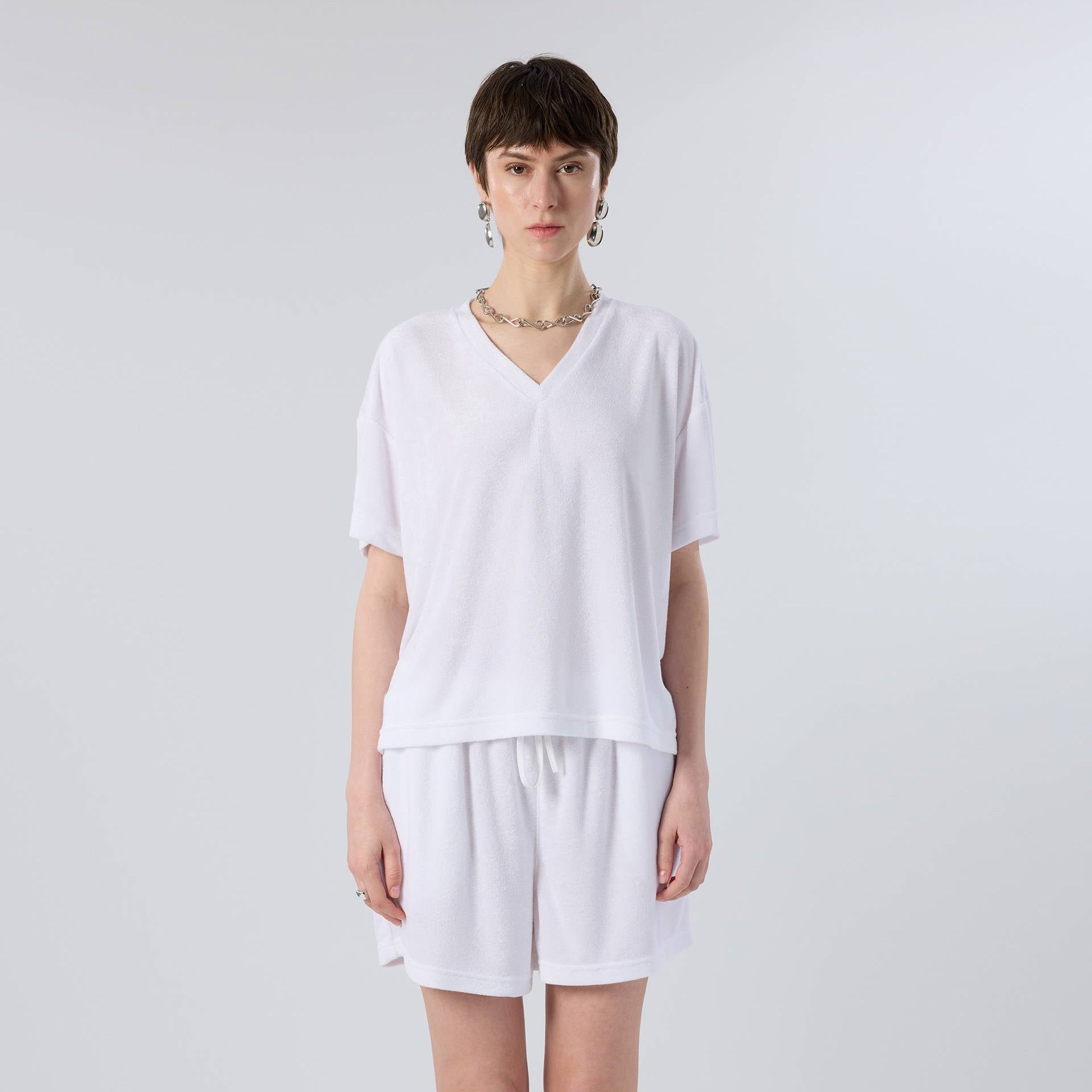 Person wearing a white outfit with shorts on a plain background