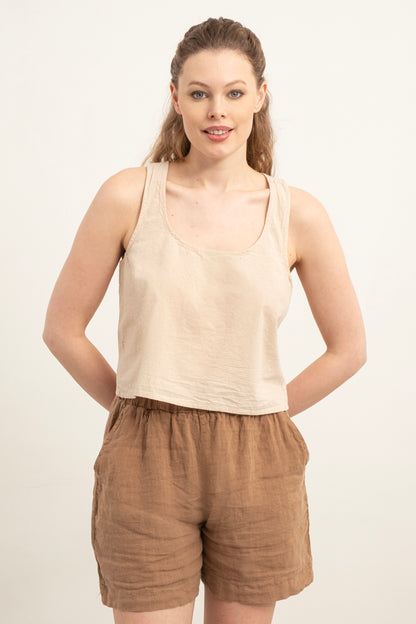 Woman wearing a beige tank top and brown shorts on a white background