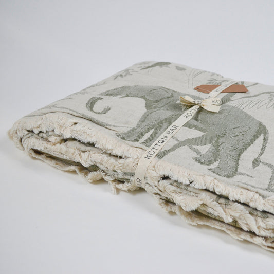 Folded blanket with elephant and fern pattern on a white background