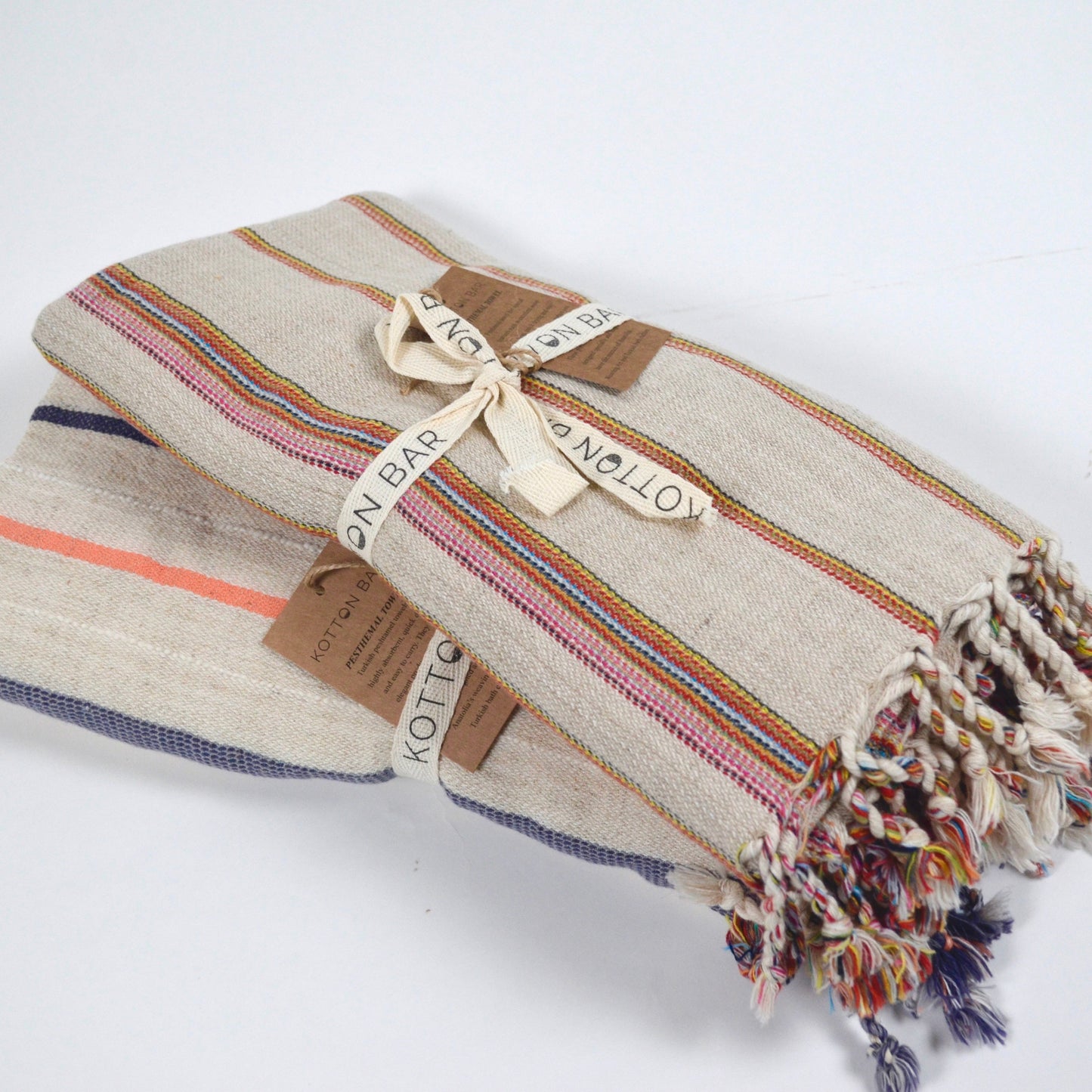 Textured blanket with colorful stripes and tassels on a white background
