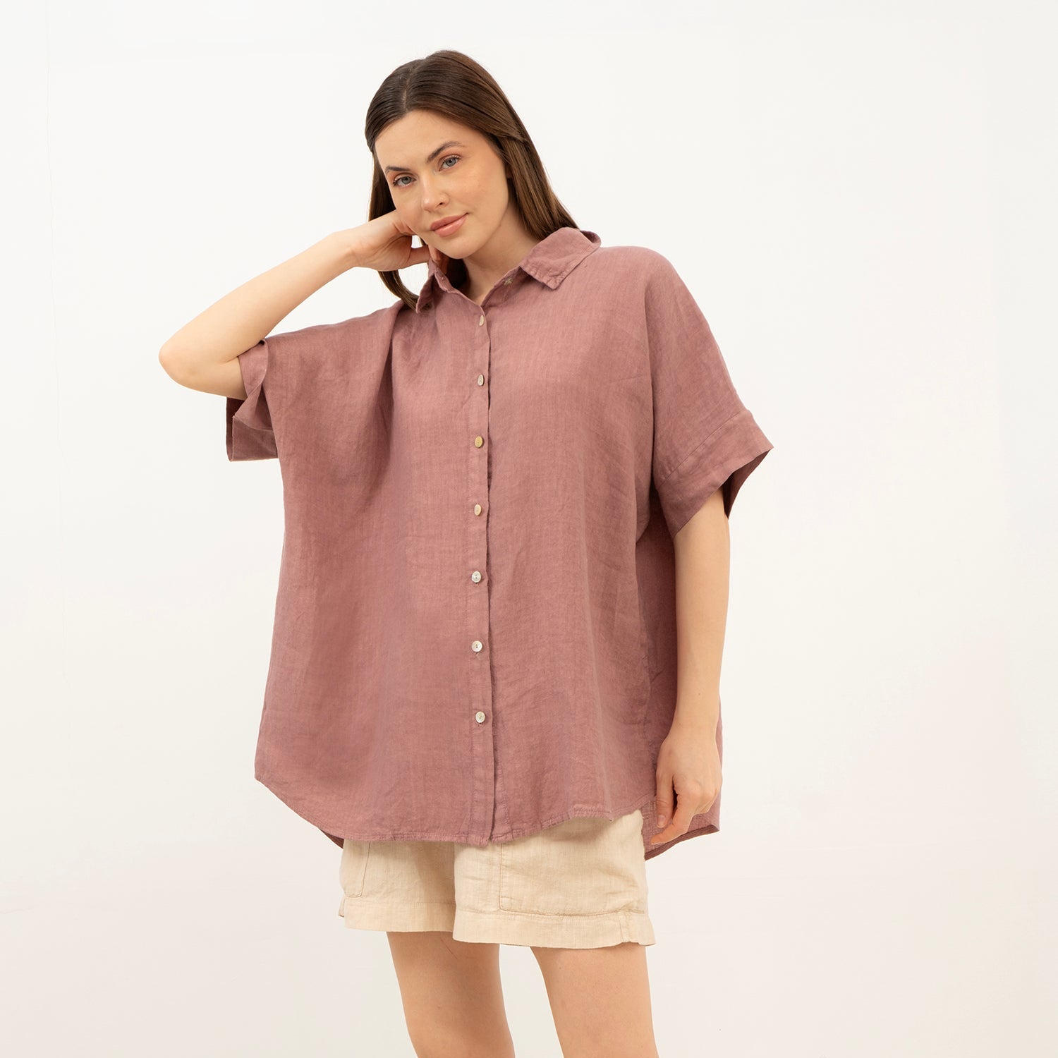 Woman wearing a mauve button-up shirt and beige shorts against a white background