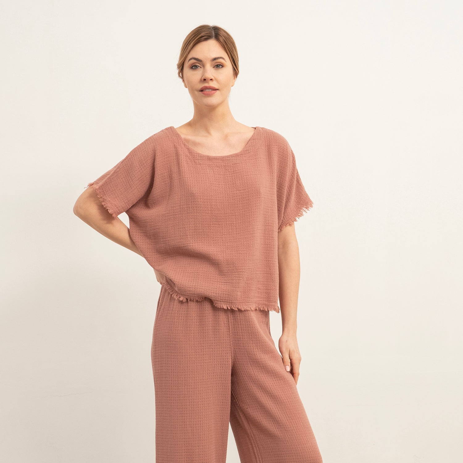 Woman wearing a brown outfit with wide-leg pants and a matching top on a white background