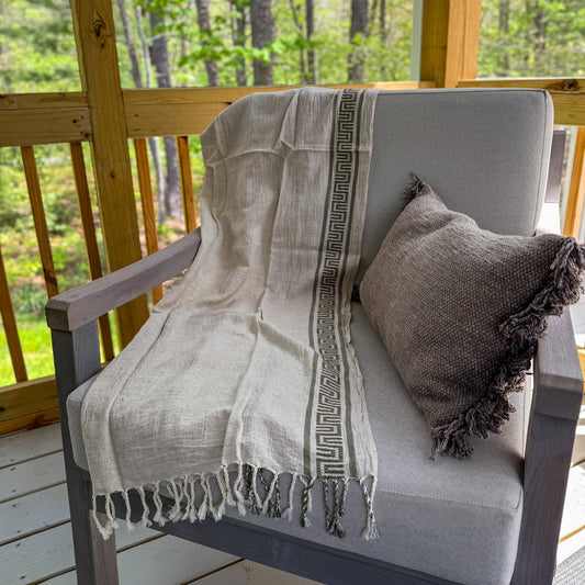 Chair with a Turkish peshtemal towel and pillow on a wooden deck with a forest view