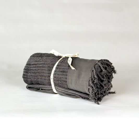 Rolled-up gray oversize Turkish cotton towel with a white tag on a light gray background