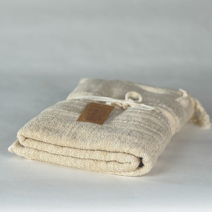 Folded beige fabric turkish cotton towel with a brown label on a light gray background