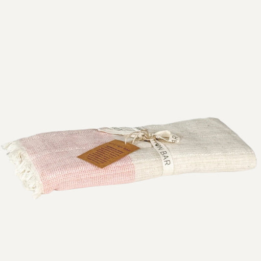 Folded pink and white fabric with a brown label on a light gray background