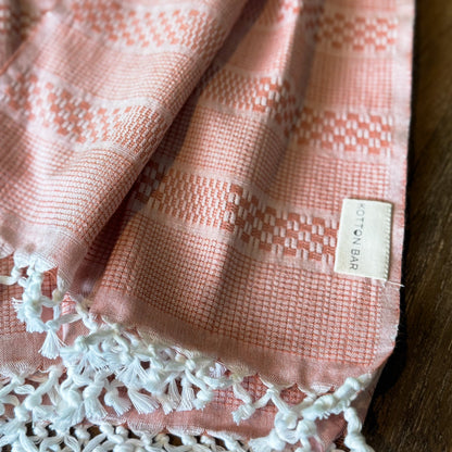 Pink textured fabric with white lace trim and a label on a wooden surface