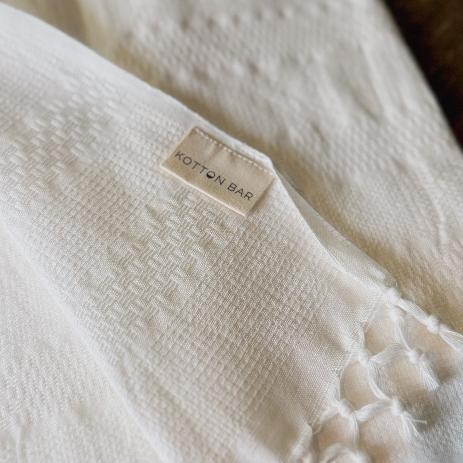 Close-up of a textured white fabric with a 'Kotton Bar' label.