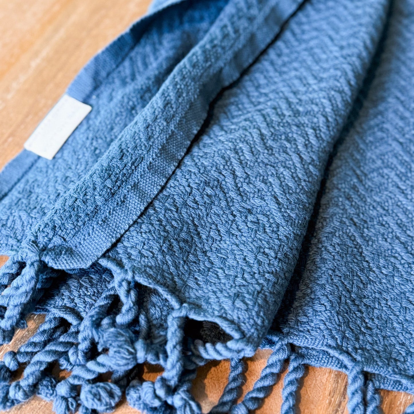 Blue towel with tassels on a wooden surface