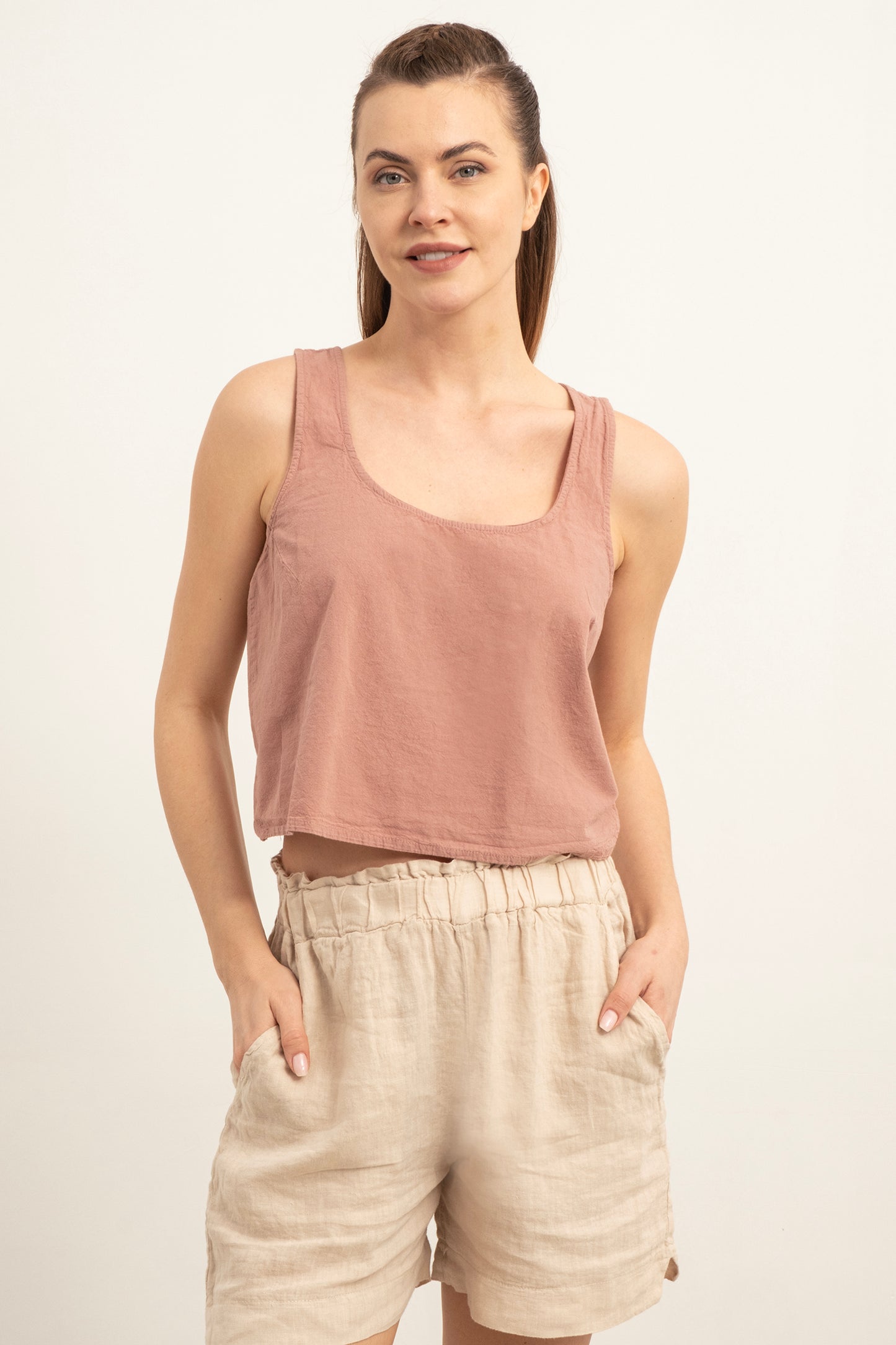 Woman wearing a pink tank top and beige shorts on a white background