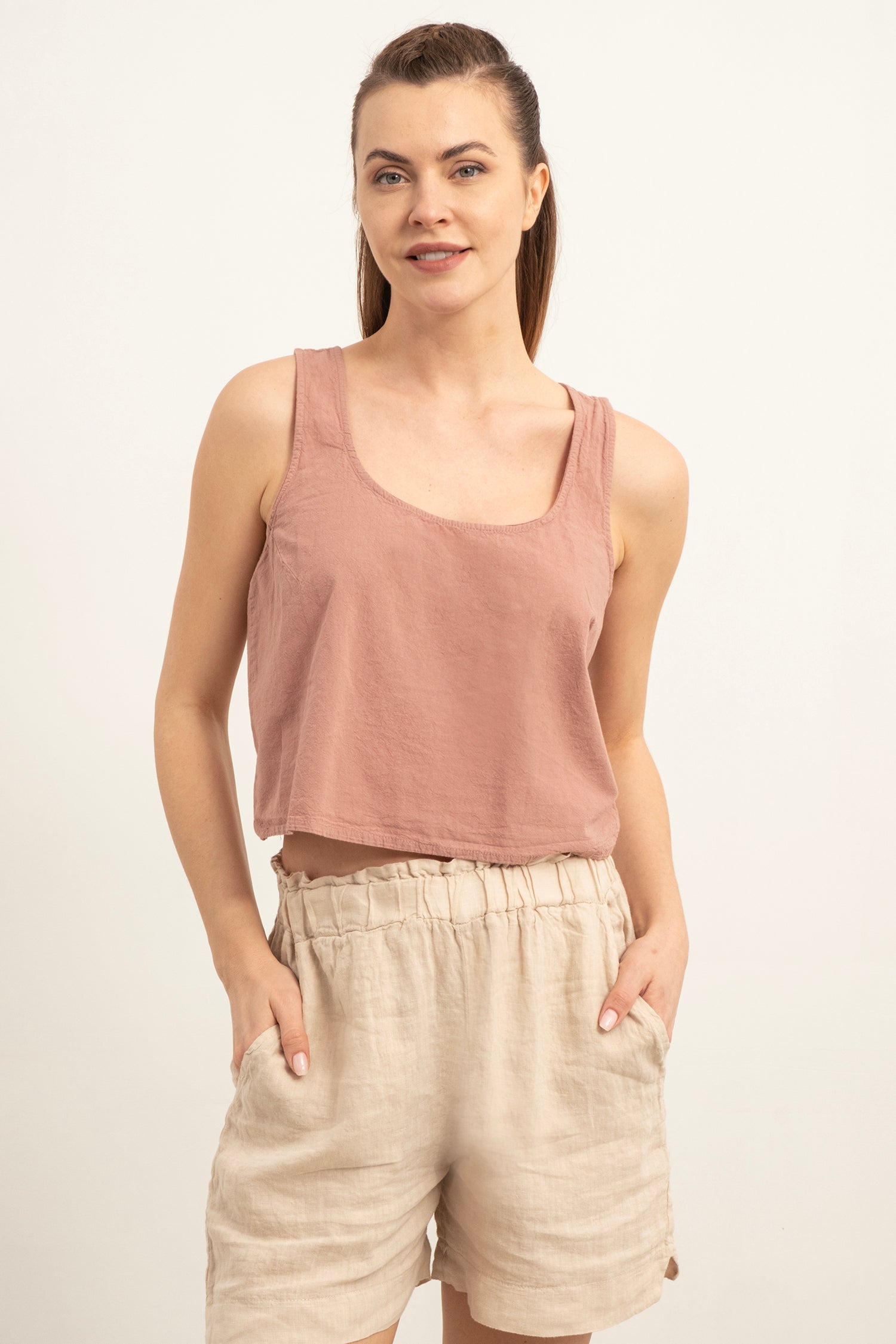 Woman wearing a pink tank top and beige shorts on a white background