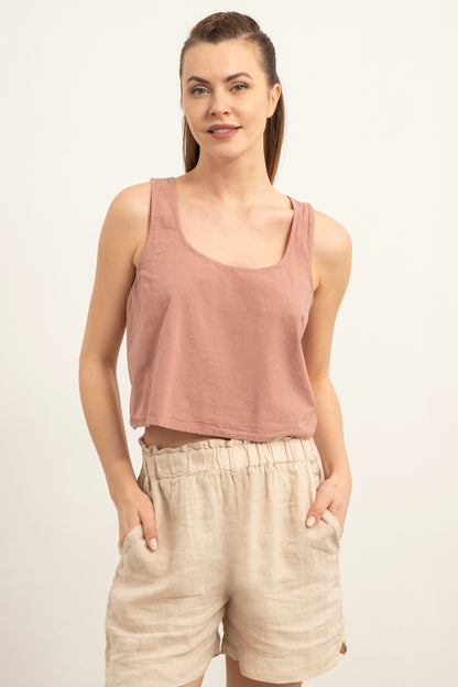Woman wearing a pink tank top and beige shorts on a white background