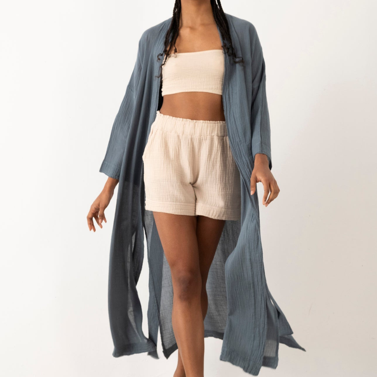 Woman wearing a long gray kimono over a white outfit on a plain background